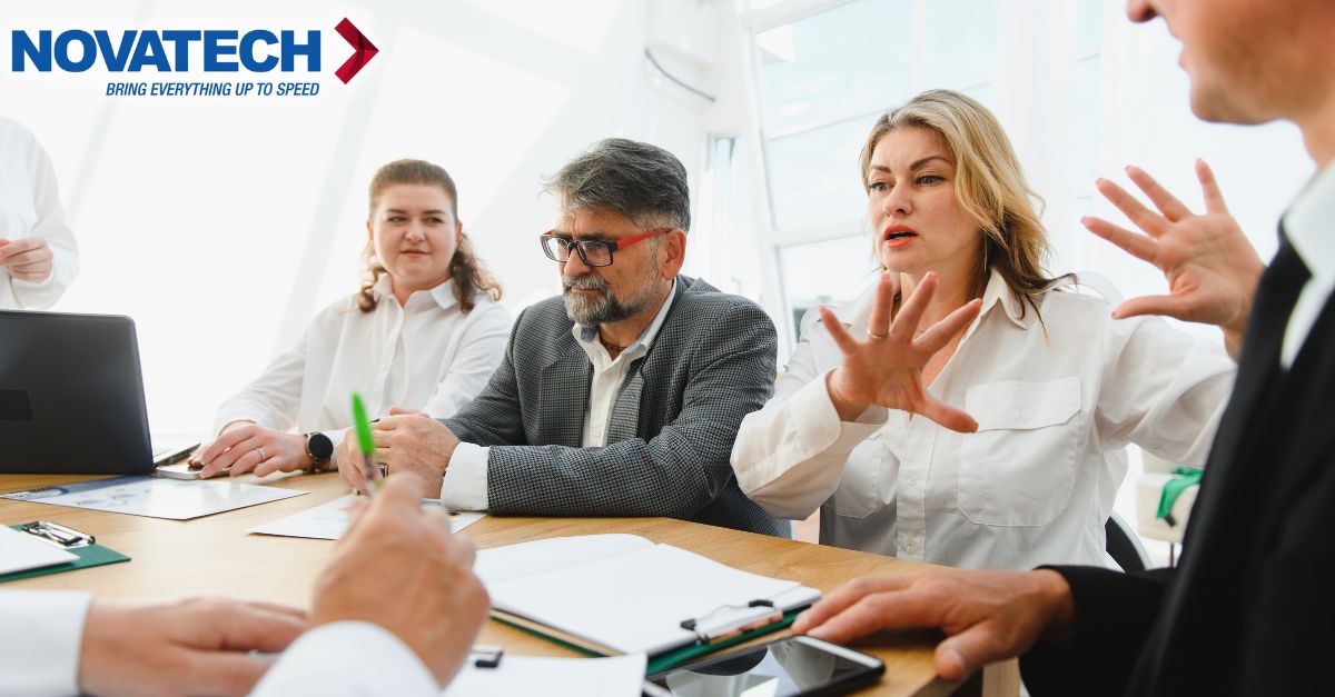 A group of professionals are engaged in a lively discussion around a conference table, with one woman gesturing
